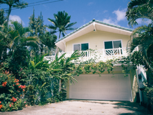 House in Maui with two stories surrounded by foliage and flowers